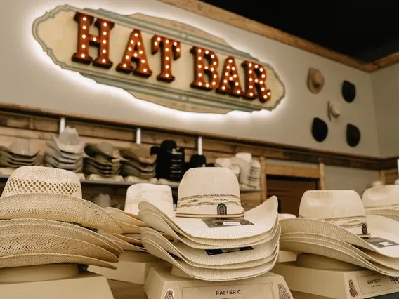 Straw cowboy hats on display under a Hat Bar sign in a Nashville shop